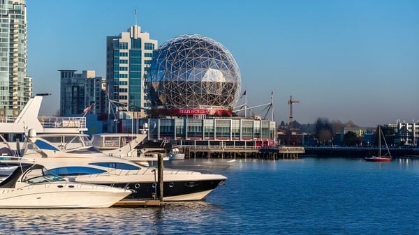 El moderno edificio de la Polyvalente Alexandre-J.-Savoie con una distintiva cúpula se encuentra en el puerto con varios barcos en primer plano.