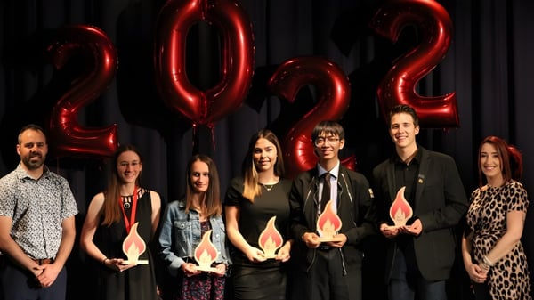 Un grupo de estudiantes posa frente a grandes globos rojos de 2022 en el campus de la Polyvalente Alexandre-J.-Savoie.