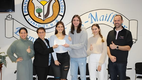 Un grupo de estudiantes está frente a un mural colorido en el campus de la Polyvalente Louis-Mailloux.