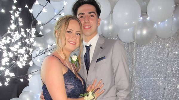 Una pareja en ropa festiva posa junta frente a luces brillantes en una celebración de la Polyvalente Louis-Mailloux.