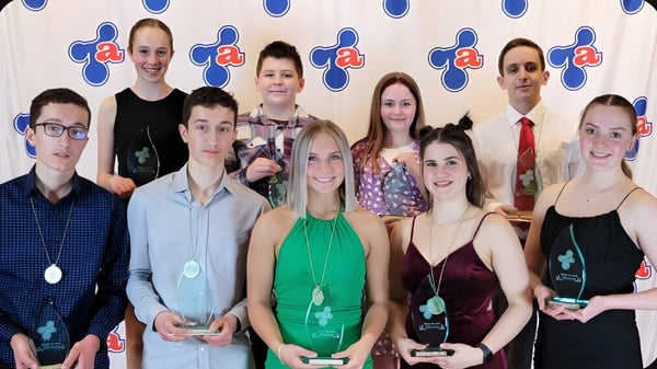 Un grupo de alumnas y alumnos de la Polyvalente Thomas-Albert posan juntos frente a un logo.