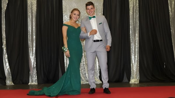 Una pareja en ropa formal está en la alfombra roja frente a una cortina plateada en el evento de la Polyvalente W.-A.-Losier.