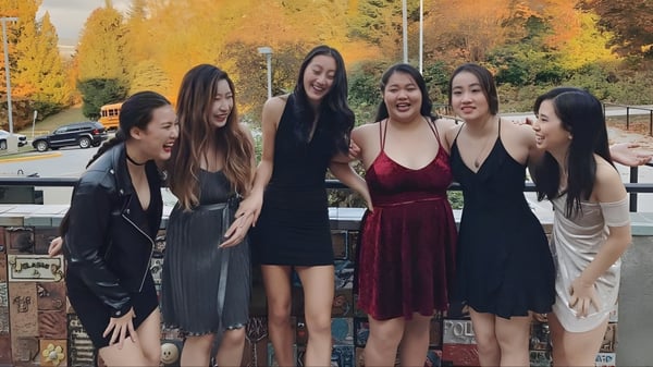 Un grupo de jóvenes estudiantes de la Port Moody Secondary School posan frente a un follaje otoñal.