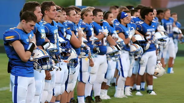 Un grupo de jóvenes atletas del Prescott Unified School District está en uniformes deportivos azules y blancos en un campo de césped.