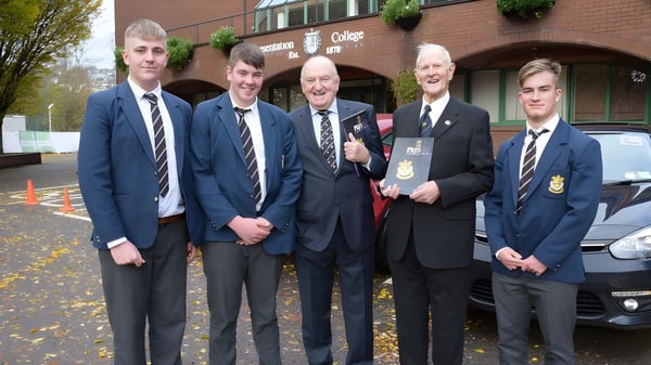 Un grupo de alumnos en uniformes escolares está frente al edificio de ladrillo de Presentation College Galway.