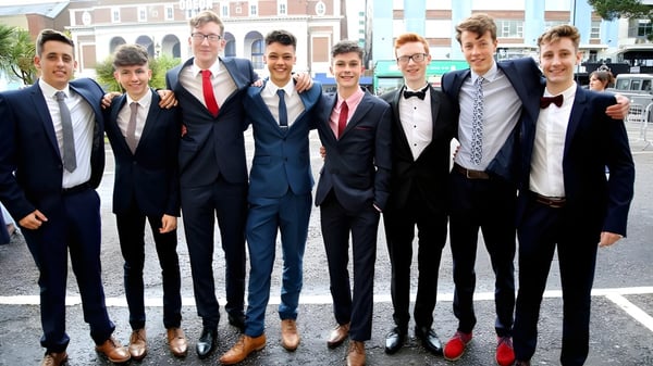 Un grupo de alumnos bien vestidos está frente a un edificio de ladrillo en el campus de Presentation College Galway.