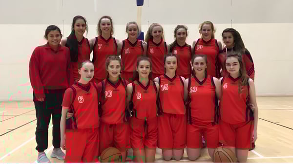 Alumnas de la Presentation Secondary School (Cork) están juntas en el gimnasio con sus camisetas rojas de baloncesto.