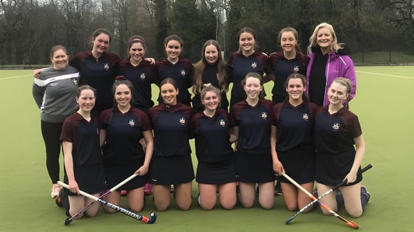 Un grupo de estudiantes de la Presentation Secondary School (Thurles) posan juntas en un campo de hierba con árboles de fondo.