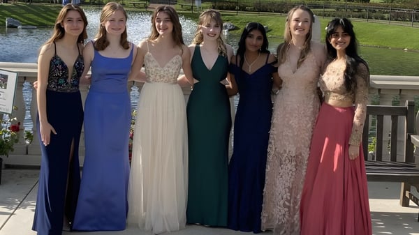 Un grupo de estudiantes de la Presentation Secondary School Thurles está en vestidos de noche frente a un paisaje con agua.