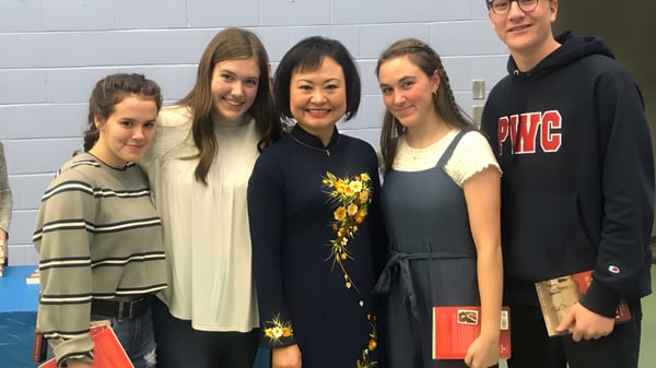 Cinco alumnas y alumnos posan juntos frente a una pared azul en el campus del Prince of Wales Collegiate.