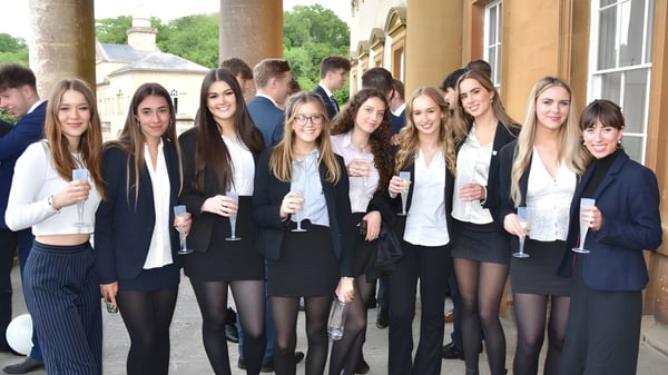 Un grupo de jóvenes mujeres vestidas de forma formal se encuentra frente a un edificio histórico en el campus del Prior Park College.