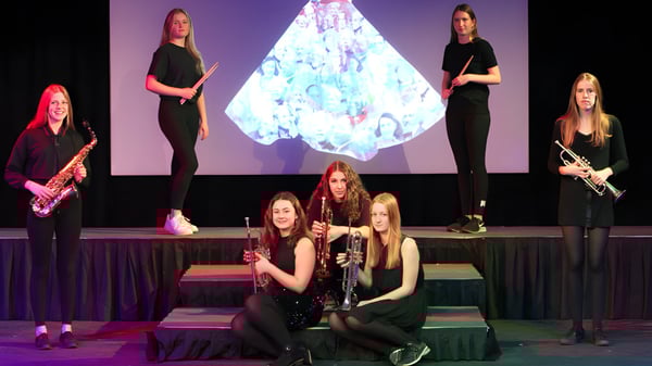 Un grupo de jóvenes alumnas actúa en el escenario de la Prior’s Field School frente a una colorida proyección de cristal.