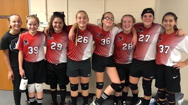 Un grupo de jóvenes deportistas posan juntos en el vestuario deportivo de la Quad Cities Christian School.