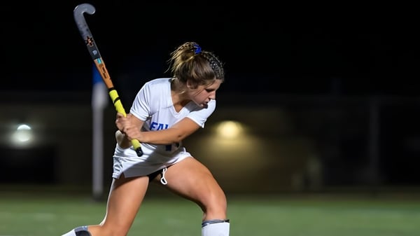 Una deportista de la Queen Anne’s School juega hockey sobre césped en un campo débilmente iluminado por la noche.
