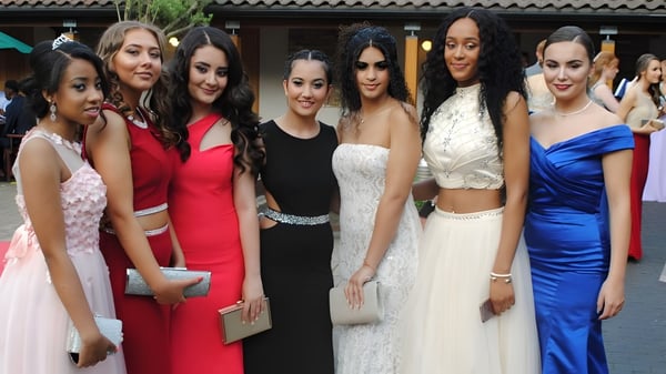 Un grupo de mujeres jóvenes vestidas formalmente se encuentra frente a un edificio con techo de tejas en el terreno de la Queen Mary's School.