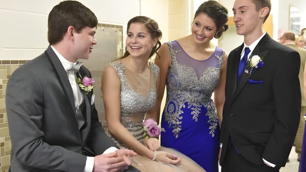 Cuatro estudiantes de la Queensbury High School están vestidos de gala en el pasillo durante un baile escolar.