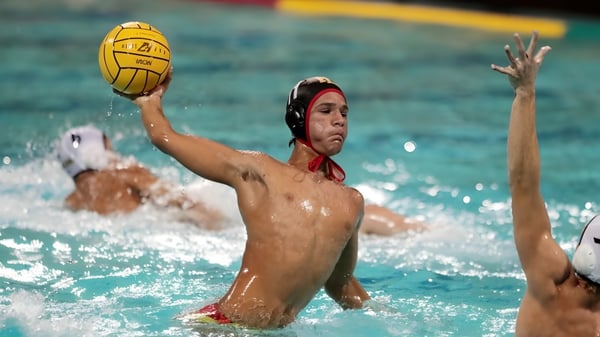 Un jugador del Radley College con gorra roja golpea la pelota amarilla en un partido de waterpolo.