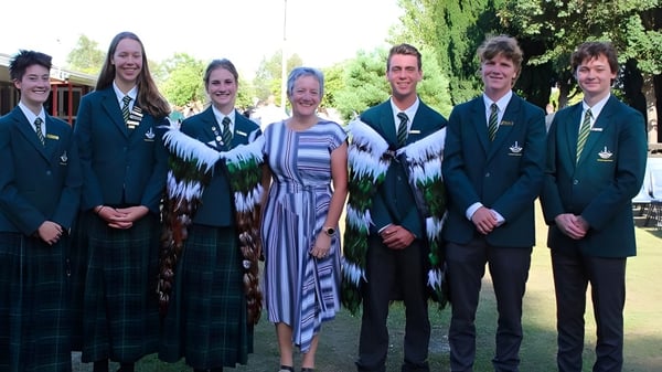 Un grupo de estudiantes de la Rangiora High School está reunido al aire libre frente a árboles y áreas verdes.