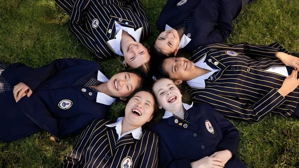 Un grupo de alumnas de la Ravenswood School for Girls está riendo sobre el césped al aire libre.