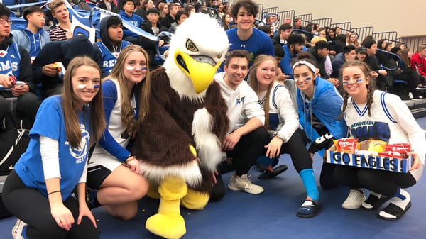 Estudiantes de la R.E. Mountain Secondary School posan con la gran mascota en un evento escolar.