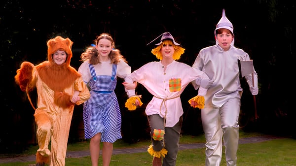 Cuatro estudiantes de la Read School caminan en coloridos disfraces por la noche bajo un cielo estrellado.