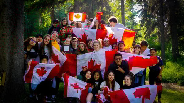Los estudiantes de Red Deer Public Schools celebran en el bosque con banderas canadienses en un evento patriótico.