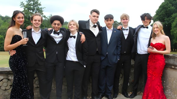 Un grupo de personas vestidas formalmente posan en el verde del campus de Reddam House Berkshire.