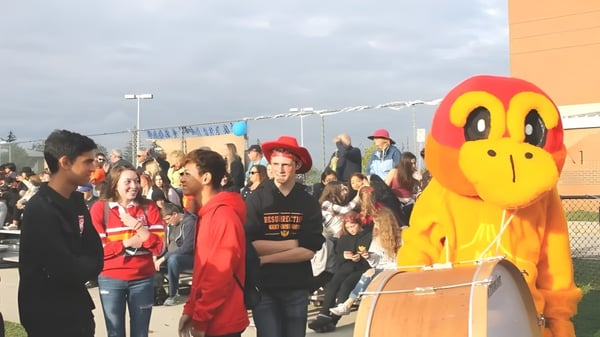 Una gran figura de dibujos animados amarilla se encuentra frente a una multitud en el terreno de la Resurrection Catholic School.