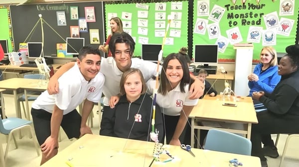 Un grupo de estudiantes de la Resurrection Catholic School trabaja juntos en una mesa en un aula colorida.
