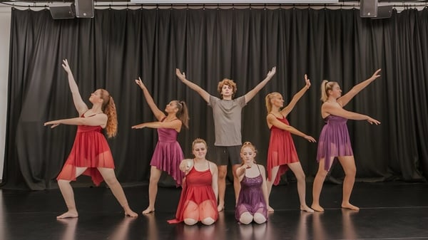 Un grupo de bailarinas y bailarines presenta una actuación de baile en el escenario del Reynella East College con coloridos trajes.