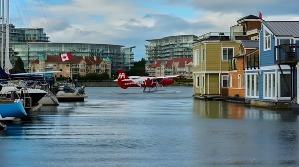 Colorida vista del agua con casas flotantes y botes frente a modernos rascacielos cerca de la Reynolds Secondary School.