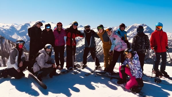 Un grupo de alumnas y alumnos de la RGS Surrey Hills posan con ropa de invierno en una pendiente nevada con un fondo montañoso.