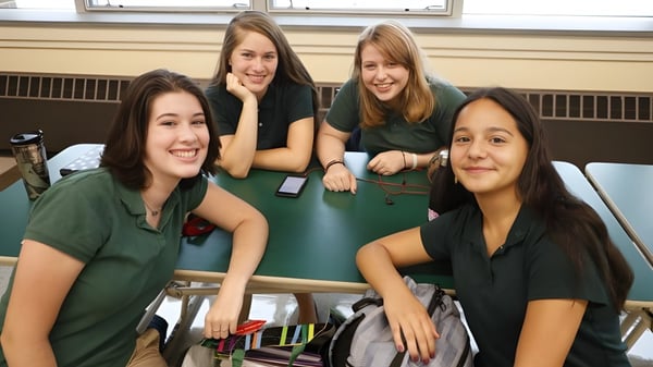 Cuatro estudiantes de la Rice Memorial High School están sentadas juntas en el aula y sonríen a la cámara.