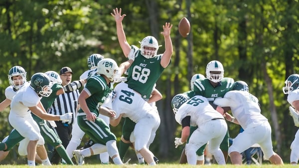 Un grupo de futbolistas en uniformes verdes y blancos juega en el campo de la Rice Memorial High School.