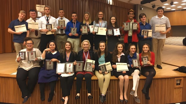 Un grupo de estudiantes de la Richmond High School está con premios frente a un escenario.