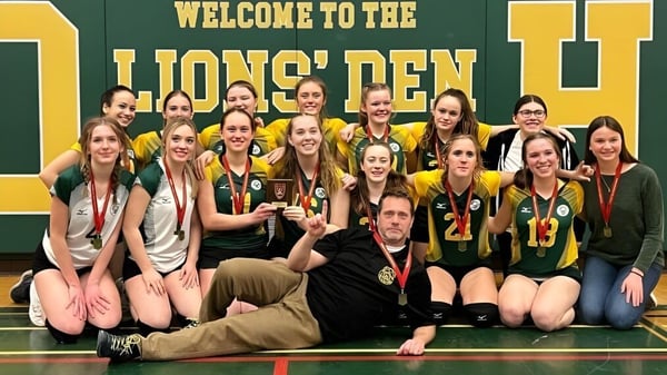 Estudiantes de la Rideau District High School se reúnen en ropa deportiva en la arena deportiva con el cartel Bienvenidos a la Guarida de los Leones.