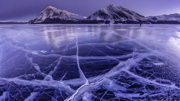 Paisaje montañoso nevado con un lago congelado frente a Ridgemont High School.