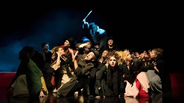 Un grupo de estudiantes de la Ringwood School está en trajes oscuros sobre un escenario con iluminación dramática.