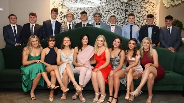 Un grupo de personas en ropa formal posan frente a un fondo floral en el campus de la Rishworth School.