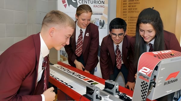 Estudiantes de la Rishworth School en uniformes escolares se reúnen alrededor de un simulador de carreras y participan en una actividad.