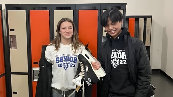 Dos estudiantes están de pie frente a los casilleros en el pasillo de la escuela River East Collegiate.