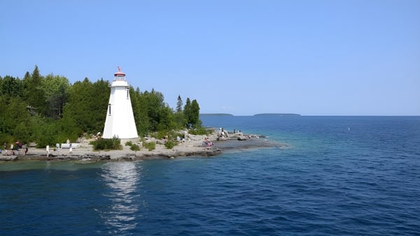 Un faro pintoresco se encuentra en un saliente rocoso rodeado de vegetación en la orilla del lago de la Riverside Secondary School.