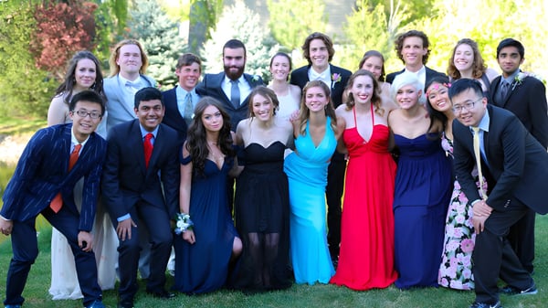 Un grupo de personas vestidas formalmente posan juntas afuera en el campus de la Riverstone International School.