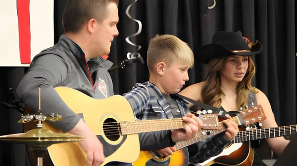 Tres estudiantes de la Riverview Middle School tocan juntos instrumentos en un aula de música.