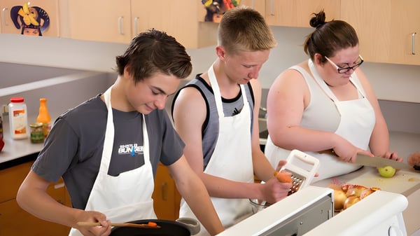 Estudiantes de la Riverview Middle School trabajan juntos en una cocina y preparan comida con utensilios de cocina.