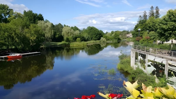 Un tranquilo lago con un bote y un muelle de madera en el terreno de la École secondaire publique Rivière Rideau.