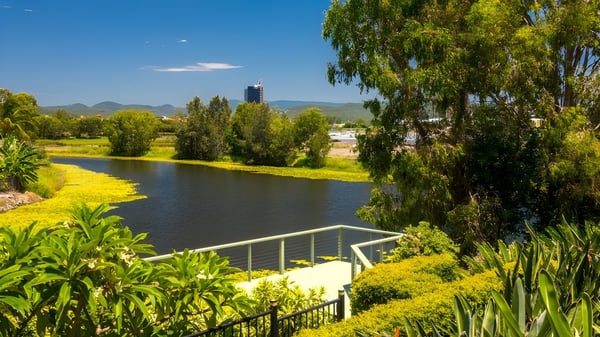 Un tranquilo paisaje fluvial con altos árboles y cielo despejado cerca de la Robina State High School.