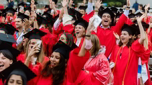 Un grupo de graduados de la Robina State High School celebra su fiesta de graduación en túnicas y birretes rojos.