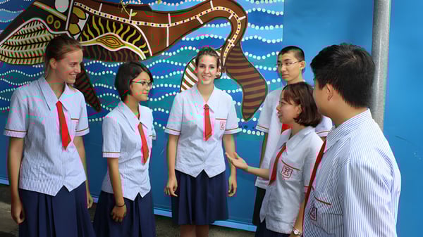Un grupo de estudiantes de la Rochedale State High School está frente a un colorido mural con patrones abstractos.