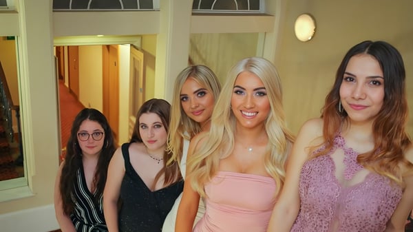 Un grupo de cinco estudiantes posan juntos en una sala con ventanas de arco en el campus de Rochester Independent College.